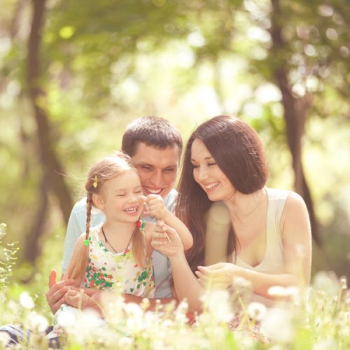 Happy mother, father and daughter playing in the park